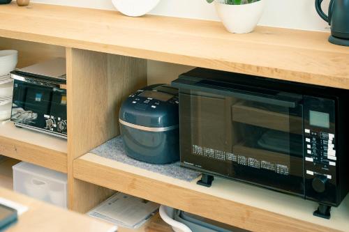 a microwave and a toaster oven on a shelf at 【海から近く】敷地内無料駐車場5台分完備！BBQ設備貸出あり3,500円！快適空間！【COQAEL】 in Oda