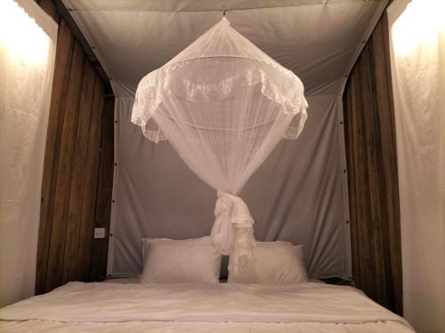 ein Himmelbett mit einem weißen Vorhang und Kissen in der Unterkunft The buh de (เดอะบูห์เดอะ) 
