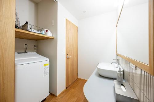 a bathroom with a washing machine and a sink at 【海から近く】敷地内無料駐車場5台分完備！BBQ設備貸出あり3,500円！快適空間！【COQAEL】 in Oda