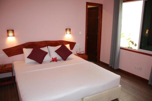 a bedroom with a white bed with two pillows at MAMELLO Beach Club Maldives in Feridhoo
