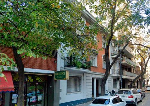 un edificio en una calle con coches aparcados delante en Apartamento Malabia en Buenos Aires