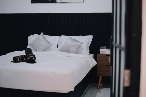 a white bed with white pillows and a black headboard at D Black Houze Banyuwangi in Banyuwangi