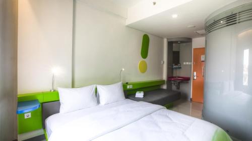 a bedroom with a large white bed and a bathroom at POP! Hotel Denpasar in Denpasar