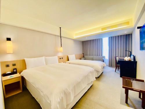 una habitación de hotel con dos camas y una mesa en Inn by the Village, en Taitung