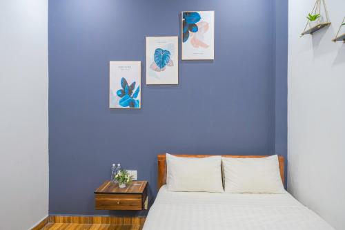 Khách Sạn Lối Về Đà Lạt في دالات: غرفة نوم بحائط ازرق مع سرير وطاولة