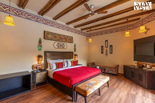 a bedroom with a large bed with a red bedspread at StayVista's Majestic Mud House - Rajasthani Architecture with Modern Amenities, Outdoor Pool, Adventure Activities, and Spa in Pushkar