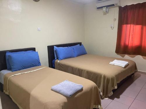 Duas camas num quarto com almofadas azuis em OYO 90914 Hotel Mei Wah em Kampong Selanchor