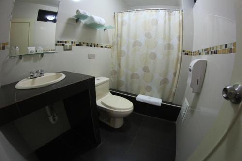a bathroom with a toilet and a sink and a shower at Posada del Rey Hotel in Trujillo