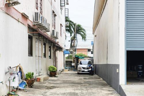 a car parked on a street between two buildings at Freesia Bangphi Guest House in Samutprakarn