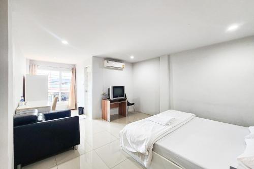 a white bedroom with a bed and a television at Freesia Bangphi Guest House in Samutprakarn