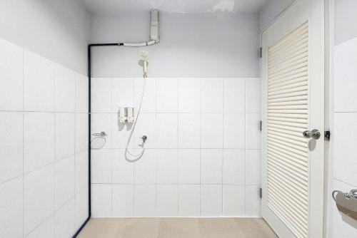 a shower in a bathroom with white tiles at Freesia Bangphi Guest House in Samutprakarn