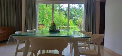 a dining room table with white chairs and a window at Wayanad Empire Colonial Villa in Kalpetta