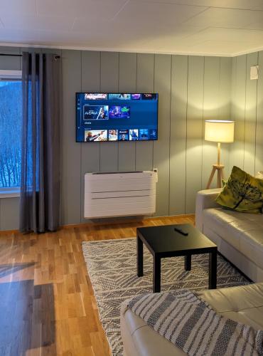 a living room with a couch and a tv on the wall at Villa Lyngenfjord in Olderdalen