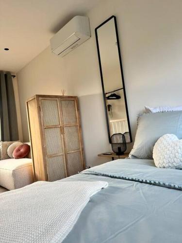 een slaapkamer met een bed met een spiegel en een bank bij Tiny House in center Aalsmeer I Close to Schiphol & Amsterdam in Aalsmeer