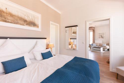 een slaapkamer met een groot wit bed met blauwe kussens bij Inselhuus Norderney in Norderney