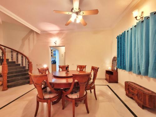 una sala da pranzo con tavolo, sedie e ventilatore a soffitto di Urban Escape Luxury Villa a Bangalore