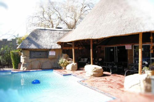 a house with a swimming pool with a thatch roof at Castle Lodge in Boksburg