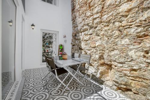 a table and chairs in a room with a stone wall at Apartamento com pátio em frente praia in Paço de Arcos