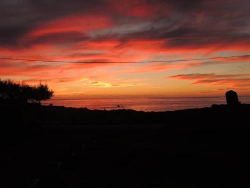 a sunset on the beach with the ocean at PARAÍSO Sunset Bungalows in Hanga Roa