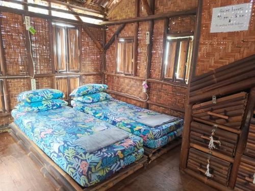 two beds in a room with wooden walls and windows at WaitHozz in Beran-kidul