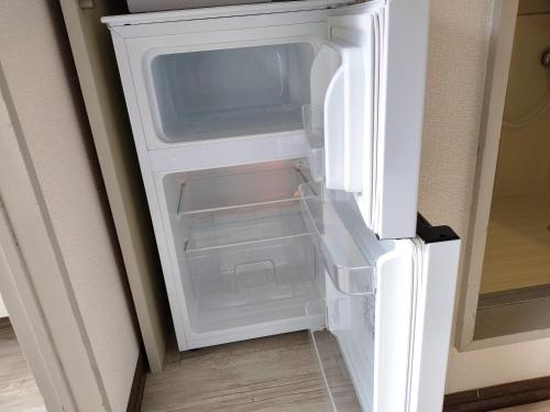 an empty refrigerator with its door open in a room at Avanti house室見 in Fukuoka