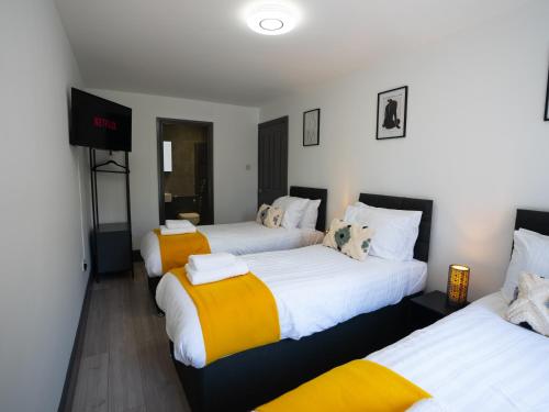 Habitación con 3 camas con sábanas blancas y amarillas. en Central Apartment 3 Beds Near Station Fee Parking en Farnborough