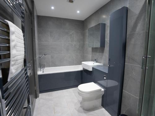 a bathroom with a toilet and a sink and a bath tub at Central Apartment 3 Beds Near Station Fee Parking in Farnborough