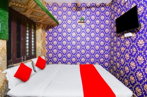 a bedroom with a bed with red pillows and a purple wall at Goroomgo Sri Jagannath Nibas Puri in Puri