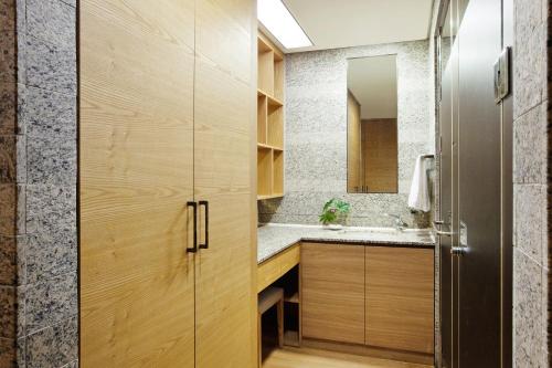 La salle de bains est pourvue de placards en bois et d'un lavabo. dans l'établissement Shin Shin Hotel Jeju Ocean, à Seogwipo