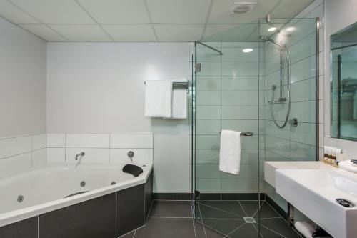 a bathroom with a tub and a shower and a sink at One88 on Commerce in Whakatane