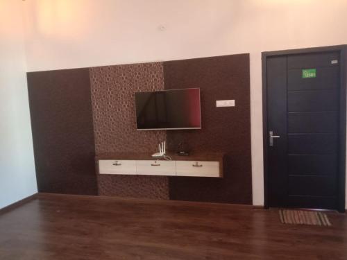a room with a tv on a wall and a door at Tulip In Green Meadows in Yercaud