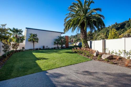 a yard with palm trees and a white fence at One88 on Commerce in Whakatane