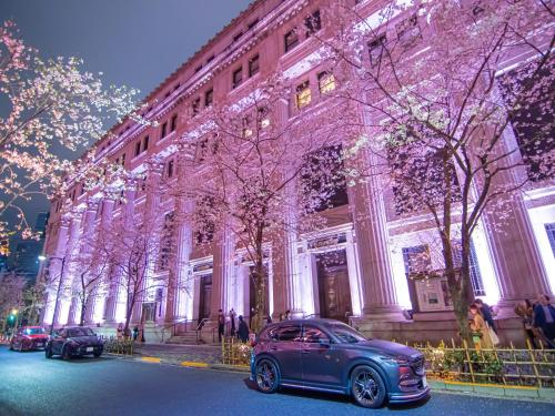 dos autos estacionados frente a un edificio con luces de Navidad en APA Hotel Ningyocho-eki Kita, en Tokio