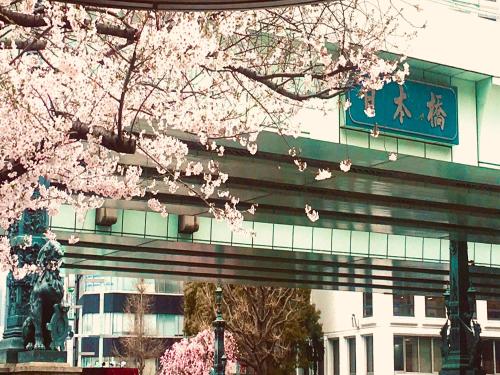 een boom met roze bloemen voor een gebouw bij APA Hotel Ningyocho-eki Kita in Tokyo