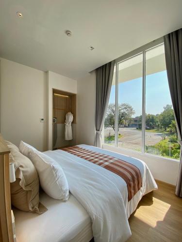 Un dormitorio con una cama grande con una ventana grande. en Punn Hotel Korat, en Nakhon Ratchasima