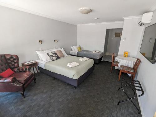 a hotel room with two beds and a chair at Toodyay Hotel in Toodyay