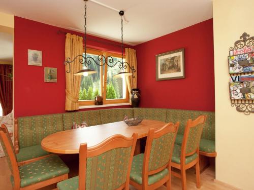 jadalnia z czerwonymi ścianami oraz drewnianym stołem i krzesłami w obiekcie Apartment in Saalbach-Hinterglemm with sauna w Saalbach Hinterglemm