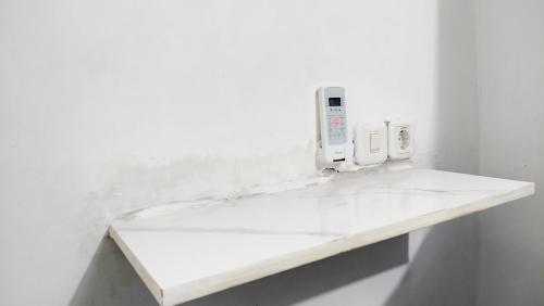 eine weiße Theke in einem weißen Raum mit einem Handy in der Unterkunft Kost Harian Semarang Murah in Semarang