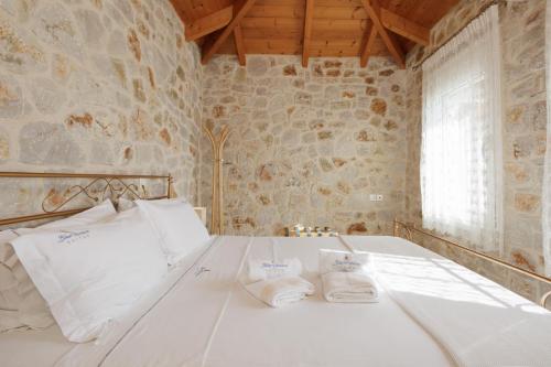 パラリオ・アストロスにあるBlue Horizon Suitesの石壁のベッドルーム1室(白いベッド1台付)