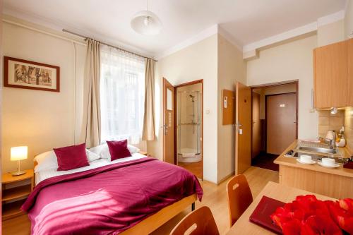 a bedroom with a large bed and a kitchen at Mały Kraków Aparthotel in Krakow