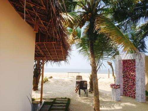 plaża z palmą, stołem i krzesłami w obiekcie Havana Beach House w mieście Alappuzha