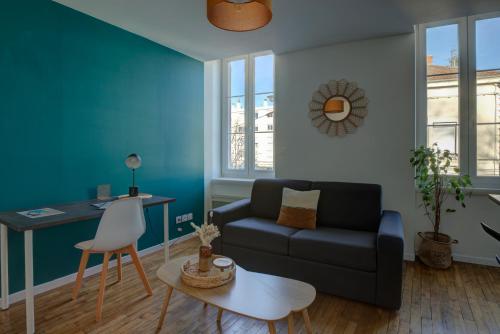 a living room with a couch and a table at Le Tournassin-Balcon-Stationnement gratuit in Bourg-en-Bresse