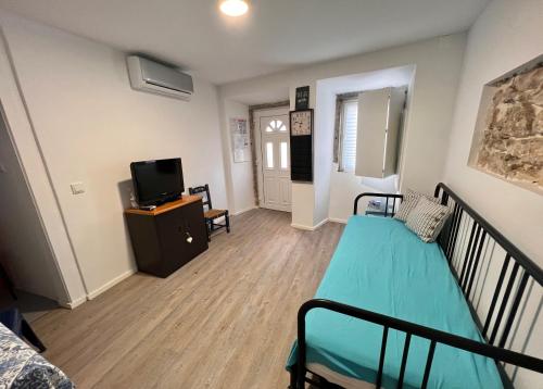 Kleines Zimmer mit einem Bett und einem TV. in der Unterkunft Apartamento com pátio em frente praia in Paço de Arcos