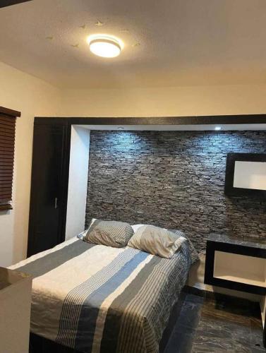 - une chambre avec un lit et un mur en briques dans l'établissement Departamentos Alex, à Cuauhtémoc