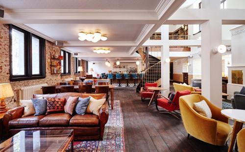 a lobby with couches and chairs and a restaurant at The Hoxton, Amsterdam in Amsterdam
