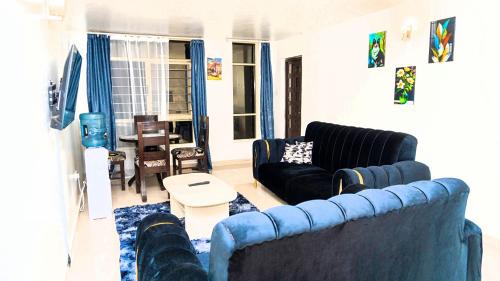 - un salon avec deux canapés bleus et une table dans l'établissement CastleHomes 1Bedroom Furnished Apartments, à Ruaka