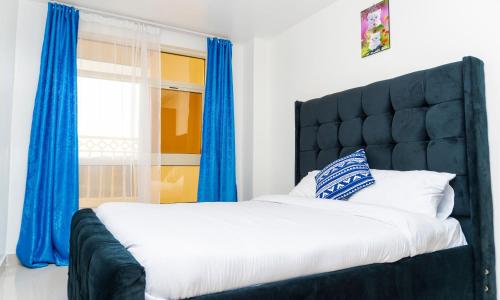 - une chambre avec un grand lit et des rideaux bleus dans l'établissement CastleHomes 1Bedroom Furnished Apartments, à Ruaka