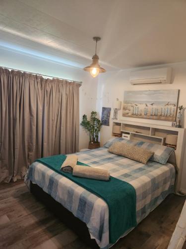 1 dormitorio con 1 cama con manta verde y blanca en Rings Road Bach, en Coromandel