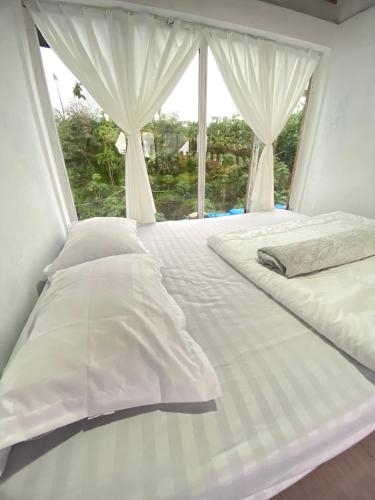 uma cama branca com uma janela num quarto em Alas Tegal villa cabin syariah em Wonosobo