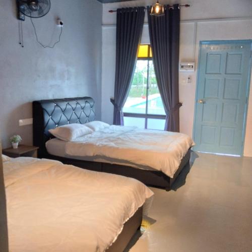 a bedroom with two beds and a window with curtains at Adana Homestay & Pool in Kangar